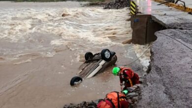 Equipe de resgate atua em área alagada com carro submerso após rompimento de estrada
