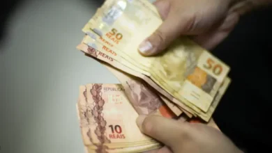 Pessoa segurando cédulas de reais, representando o pagamento da segunda parcela do 13º salário do INSS