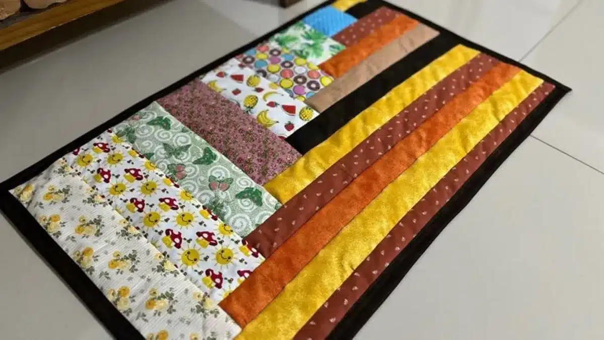 Tapete de retalhos feito com faixas de tecidos coloridos e estampados, costurados lado a lado.