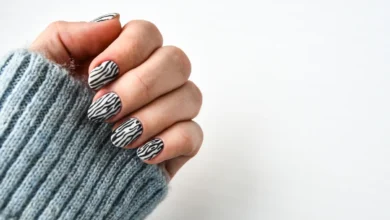 Unhas com esmalte preto e branco em padrão zebra, com suéter cinza de lã.