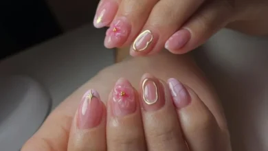 Unhas decoradas com textura em tons de rosa, com flores 3D e contornos dourados