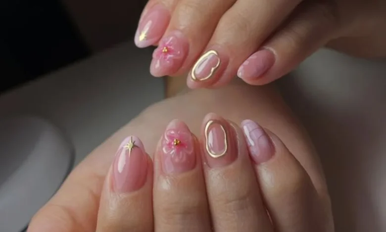 Unhas decoradas com textura em tons de rosa, com flores 3D e contornos dourados