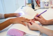 Esteticista aplicando unhas de gel em cliente com foco em detalhes.