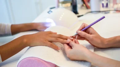Esteticista aplicando unhas de gel em cliente com foco em detalhes.