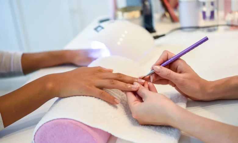 Esteticista aplicando unhas de gel em cliente com foco em detalhes.