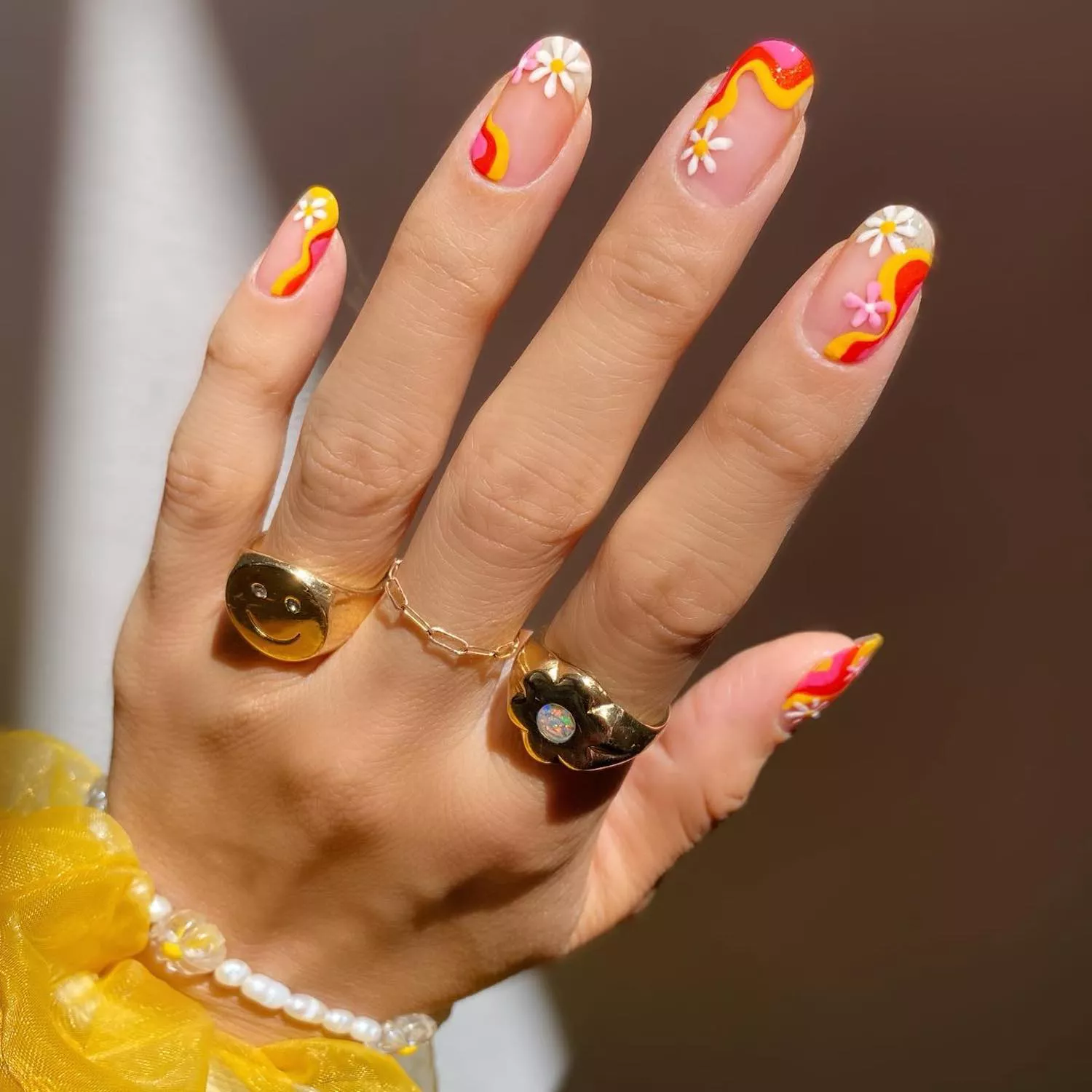 Unhas decoradas com flores e tons quentes de vermelho, amarelo e rosa para a festa de São João.