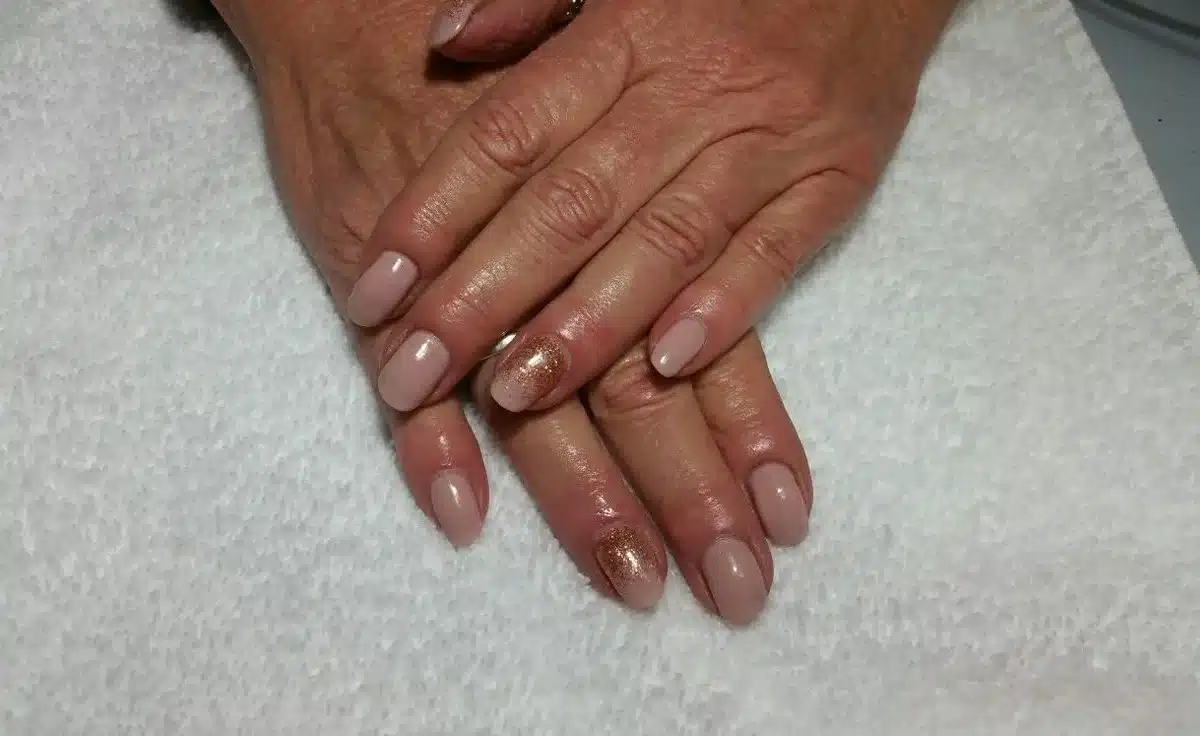 Unhas artísticas em tonalidade discreta com detalhe dourado para mulheres maduras, sofisticadas e elegantes.