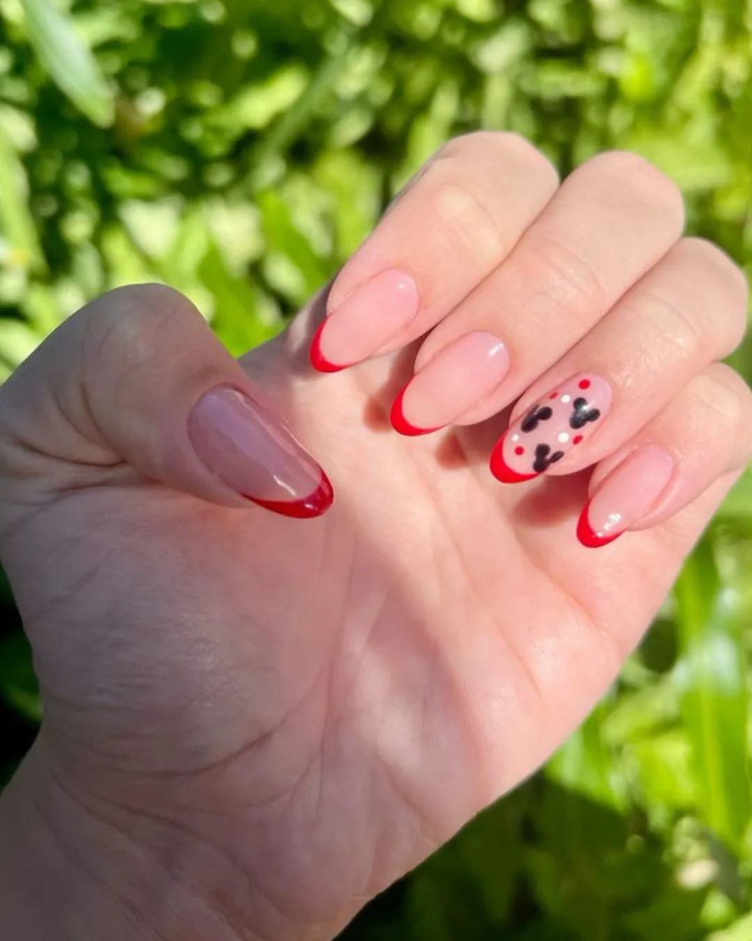 Unhas francesinhas com ponta vermelha e detalhes de corações vermelhos e pretos, um toque romântico e criativo.