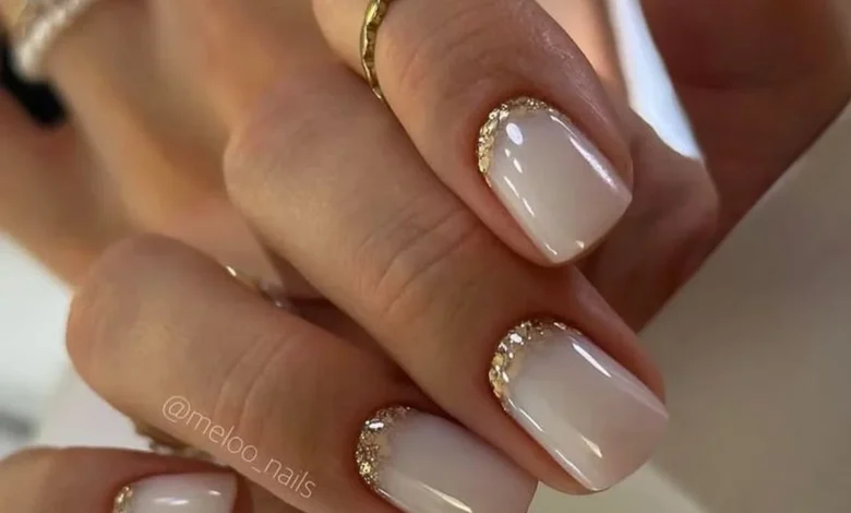 Unhas decoradas para noiva com acabamento nude e detalhes dourados na ponta, estilo elegante e sofisticado.