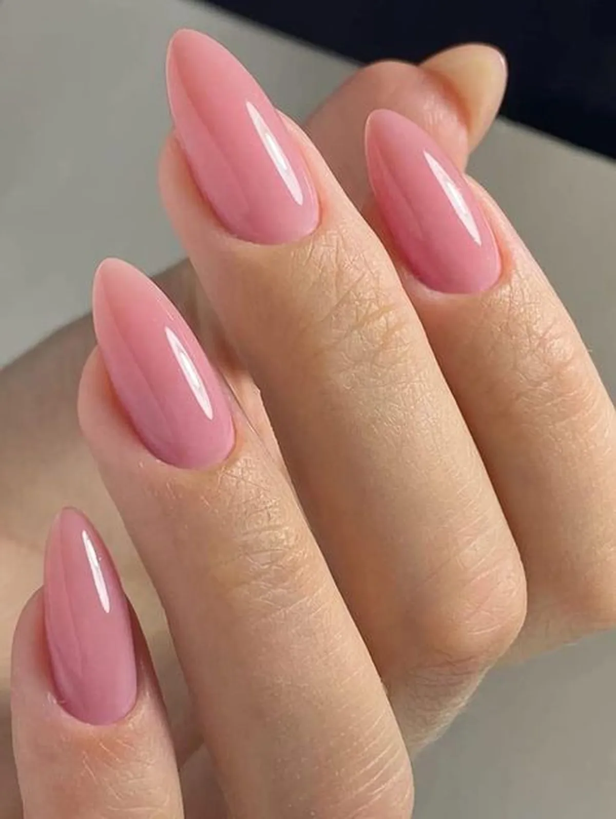 Unhas médias em formato oval e tom rosa claro, ideais para um visual elegante para quem trabalha com digitação.