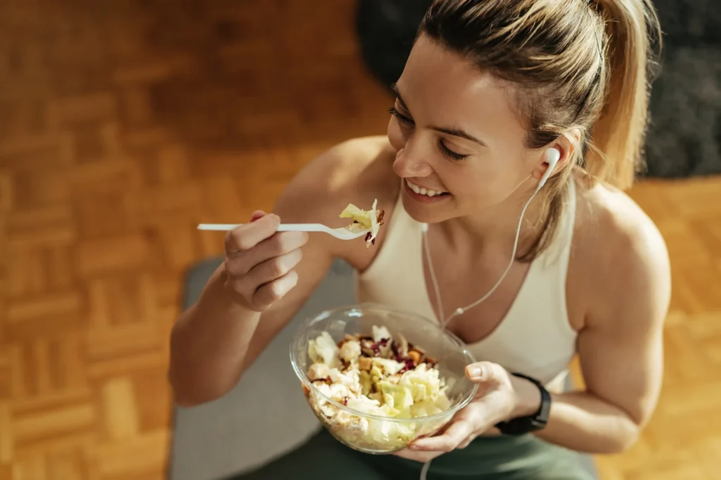 Mulher desfrutando de uma refeição saudável, comendo uma salada após treino