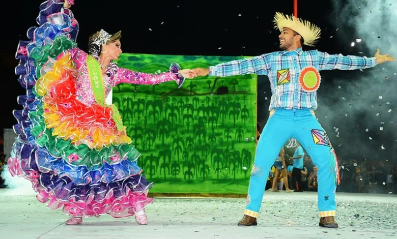 Casal dançando quadrilha com trajes típicos de São João, com chapéu de palha e roupas coloridas.