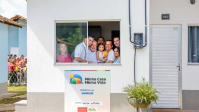 Família sorridente na janela de casa do programa Minha Casa, Minha Vida 2025