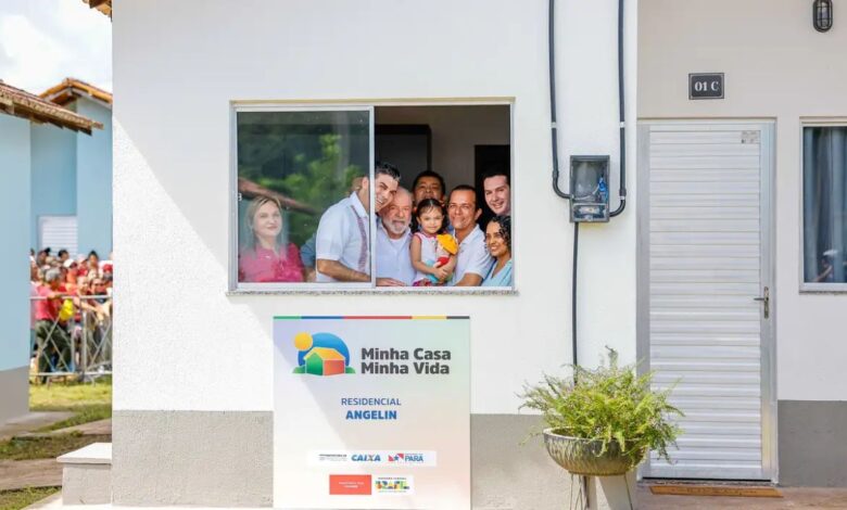 Família sorridente na janela de casa do programa Minha Casa, Minha Vida 2025
