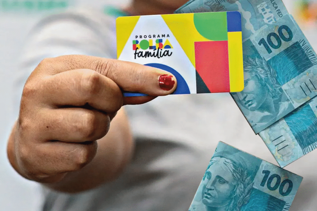 Mulher segurando o cartão do novo Bolsa Família com notas de 100 reais ao fundo