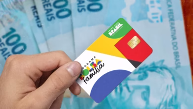 Cartão do programa Bolsa Família em frente a notas de R$100, simbolizando as mudanças e exclusões recentes no programa.