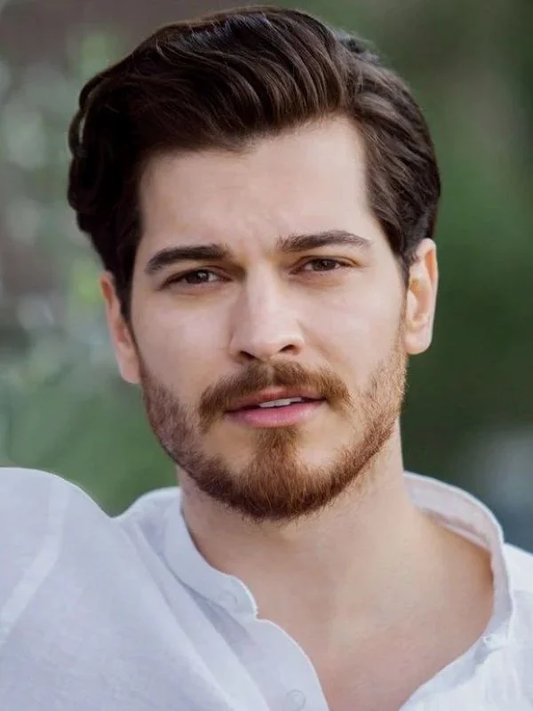 Çağatay Ulusoy, ator turco, com barba e cabelo estiloso, posando para a foto.