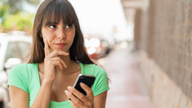 Mulher segurando celular com expressão de dúvida em ambiente urbano