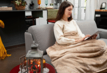 Mulher usando manta no sofá para se aquecer durante o frio em casa
