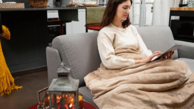 Mulher usando manta no sofá para se aquecer durante o frio em casa