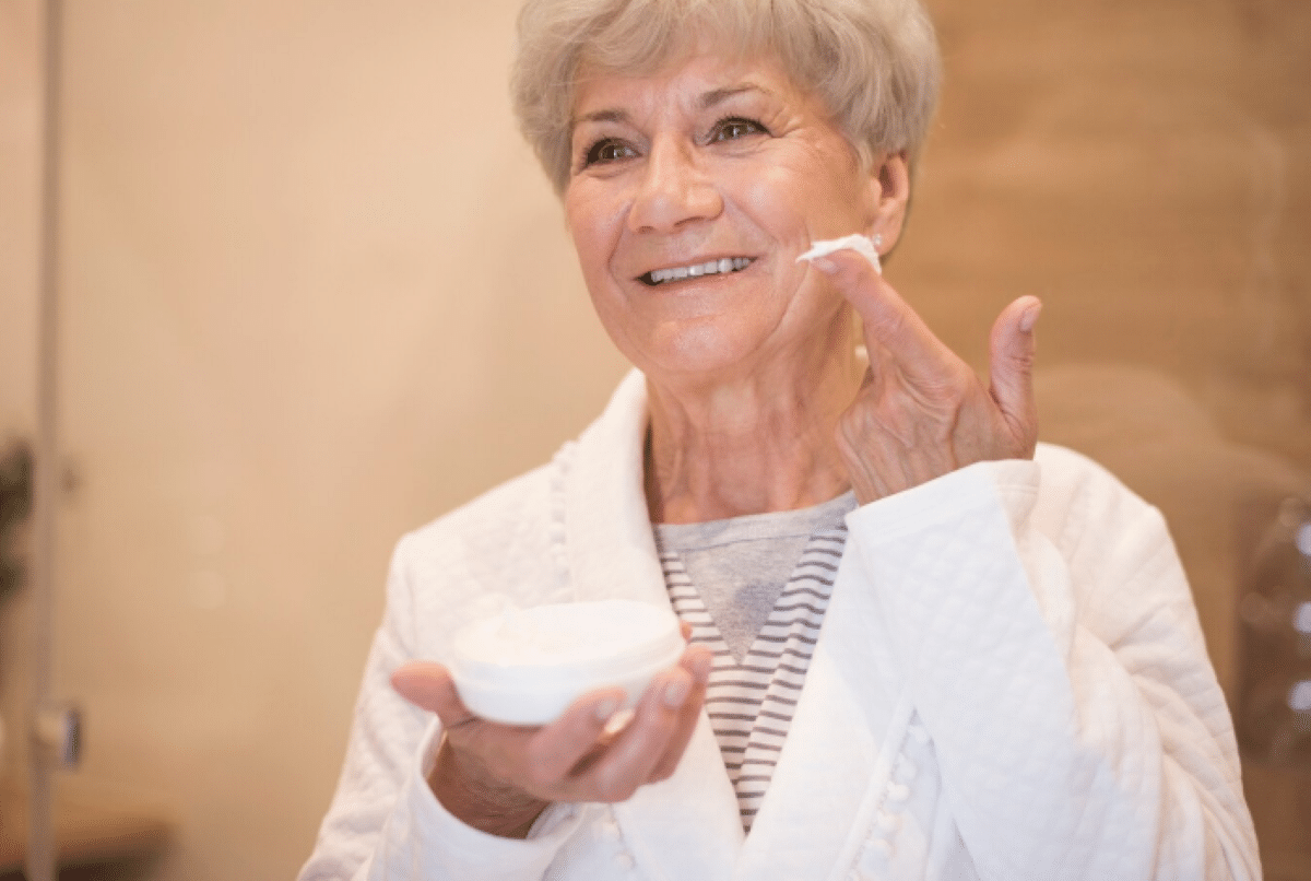 Idosa aplicando hidratante no rosto durante o inverno para manter a pele saudável