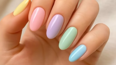Unhas de esmalte pastel em tons suaves de amarelo, rosa, lilás, verde e azul, combinando com a tendência de cores delicadas e vibrantes.