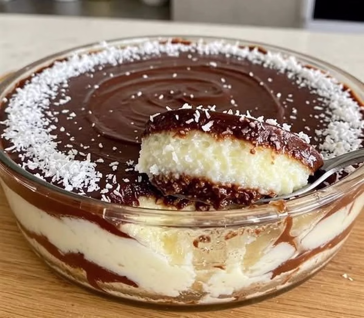 Gelado de coco com chocolate, uma sobremesa refrescante com camadas de coco e chocolate, coberta com coco ralado, em uma tigela.