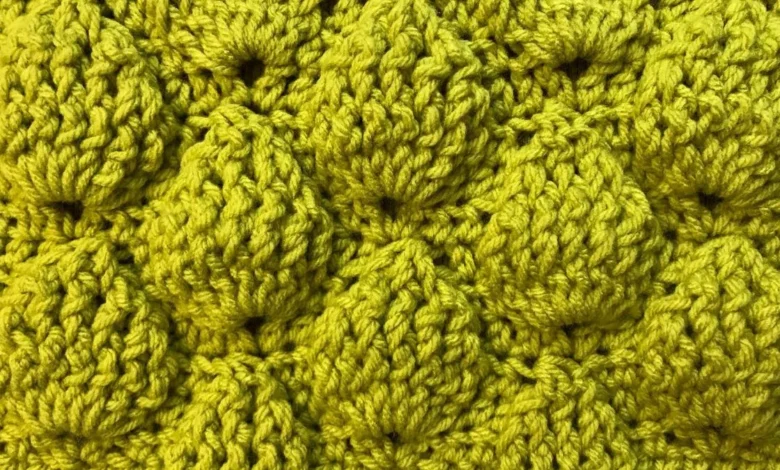 Detalhe de manta de crochê com ponto abacaxi em tom de amarelo, mostrando o relevo e a textura das camadas.