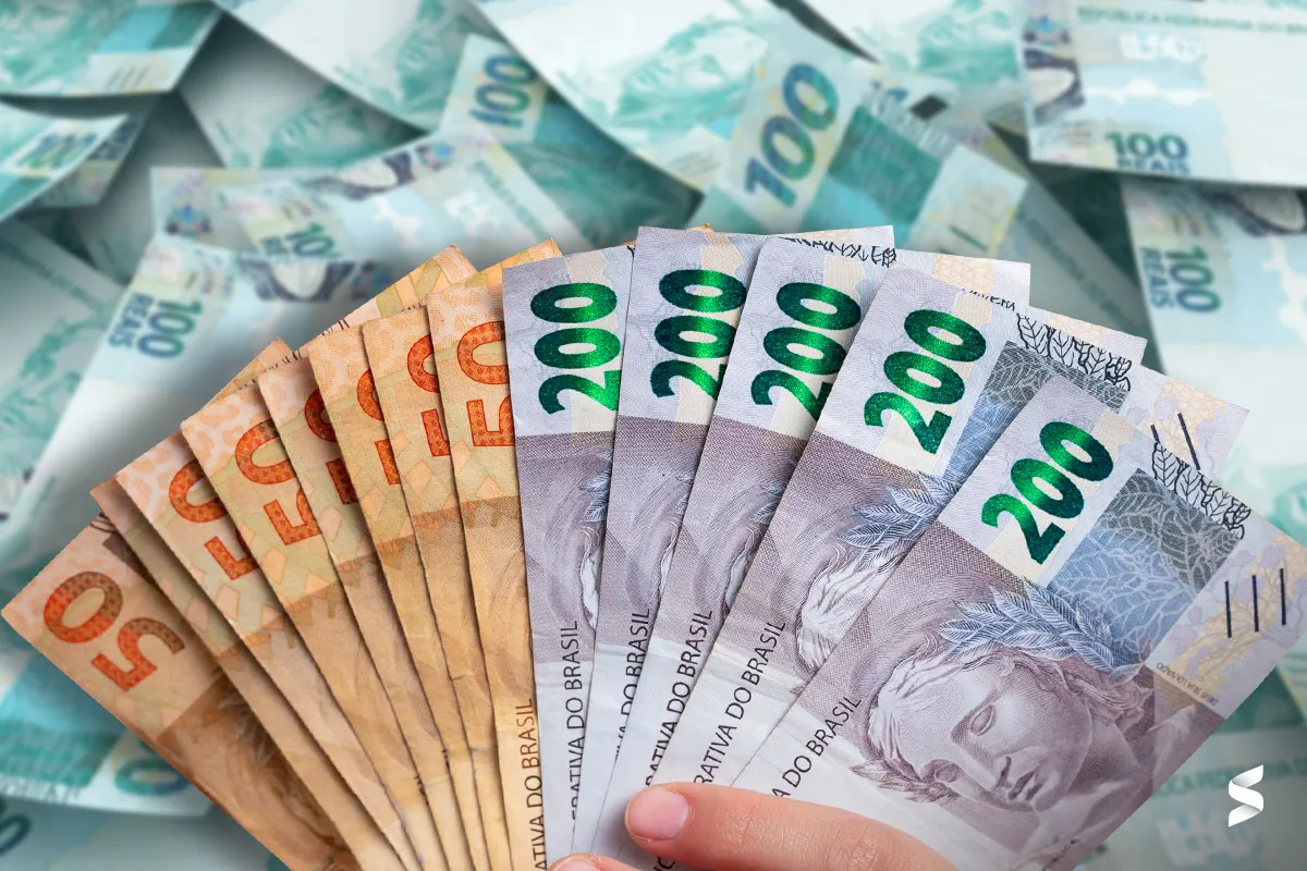 Notas de dinheiro, incluindo cédulas de 50 e 200 reais, representam a queda no uso de dinheiro físico no Brasil, com a digitalização dos meios de pagamento.