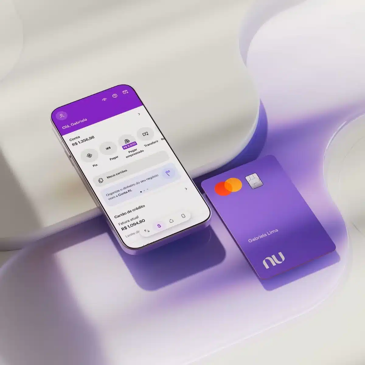 Imagem do aplicativo Nubank aberto em um celular com o cartão Nubank roxo ao lado, mostrando informações da conta do usuário.
