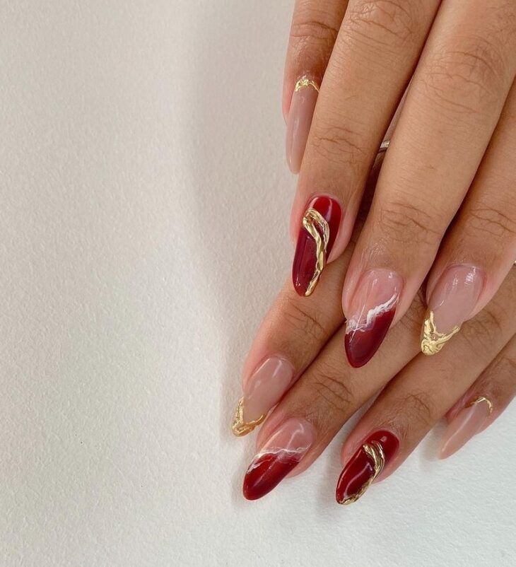 Unhas vermelhas com detalhes dourados e acabamento artístico