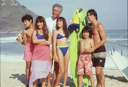 Cena da novela A Gata Comeu, com o elenco principal na praia, destacando a descontração e o humor da trama.