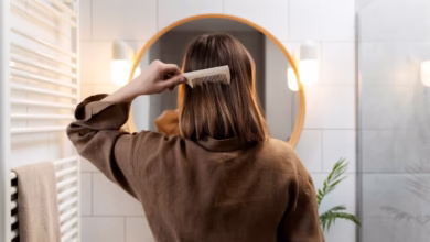 Mulher escovando cabelo em frente ao espelho, demonstrando um penteado rápido e simples.