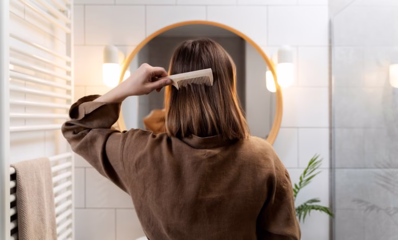 Mulher escovando cabelo em frente ao espelho, demonstrando um penteado rápido e simples.