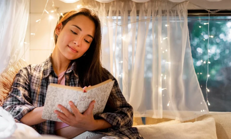 Mulher lendo um livro em um ambiente acolhedor com luzes suaves ao fundo, refletindo a calma e o relaxamento antes de dormir.