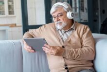 Idoso com fones de ouvido utilizando tablet para aprender com tecnologia