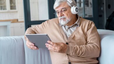Idoso com fones de ouvido utilizando tablet para aprender com tecnologia