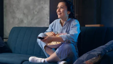 Mulher jovem assistindo série ou novela turca em serviço de streaming, com uma tigela de pipoca nas mãos.