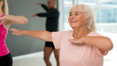 Idosa sorrindo durante uma aula de atividades físicas adaptadas para idosos, como zumba.