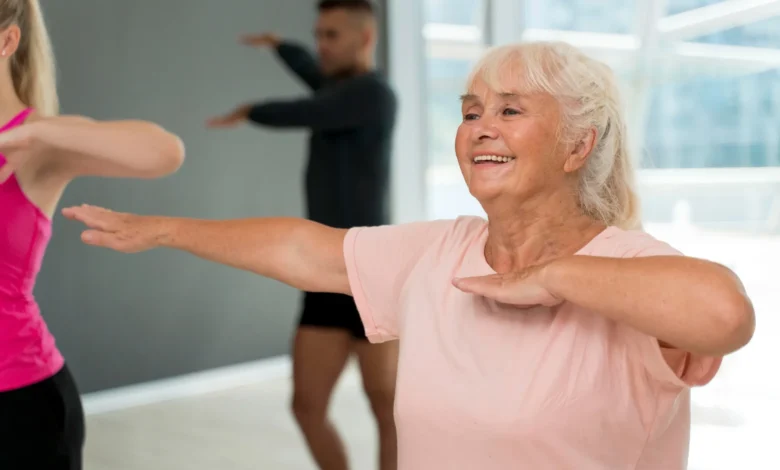 Idosa sorrindo durante uma aula de atividades físicas adaptadas para idosos, como zumba.