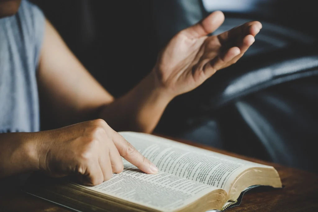 Mãos em oração sobre uma Bíblia Sagrada, representando a tranquilidade e a conexão espiritual ao ler os Salmos antes de dormir.