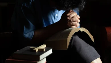 Pessoa orando com a Bíblia em um ambiente tranquilo, refletindo a fé e o conforto espiritual.