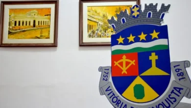 Brasão de Vitória da Conquista, cidade da Bahia, com detalhes de uma cruz, uma espada, e estrelas, no contexto de alerta sobre cadastro habitacional gratuito.