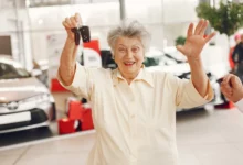 Mulher sorridente segurando as chaves de um carro novo na melhor idade.