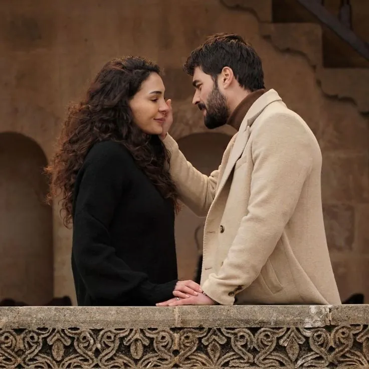 Casal apaixonado em cena romântica de novela turca com cenário histórico.