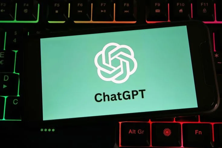 Imagem de um smartphone exibindo o logo do ChatGPT em uma tela verde, com um teclado iluminado ao fundo.