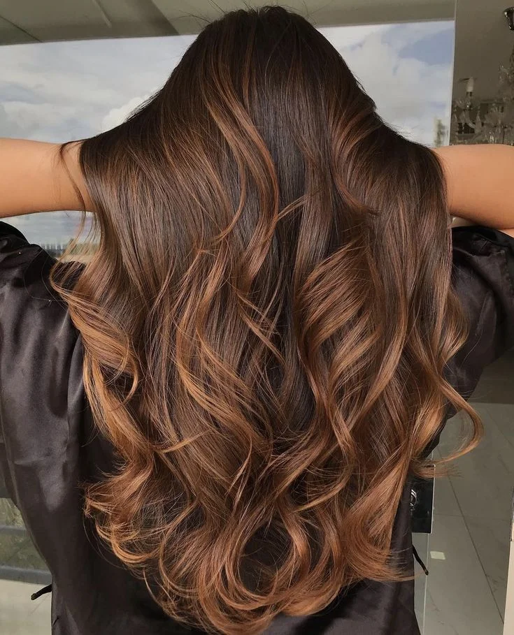 Cabelos com tonalidade chocolate dourado, com reflexos iluminados e sofisticados.