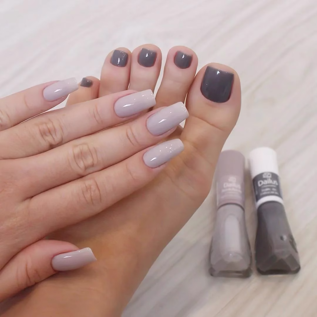 Unhas das mãos e dos pés combinando esmaltes em tons de cinza e bege, criando um visual elegante e harmonioso.