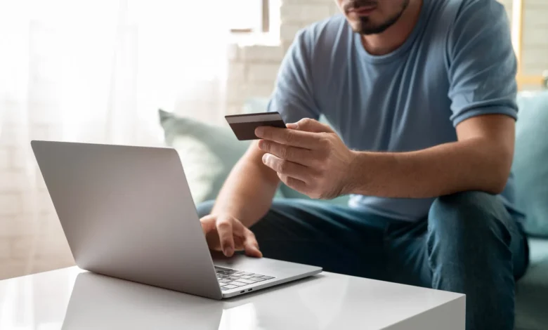 Homem usando cartão de crédito para realizar compras online com segurança.
