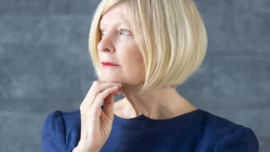 Mulher madura com cabelo chanel elegante, vestindo um vestido azul, olhando para o futuro com expressão pensativa. O corte de cabelo chanel traz sofisticação e modernidade.
